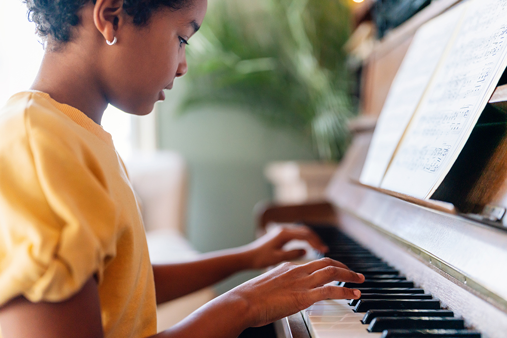 Uma criança lendo partituras e tocando piano.