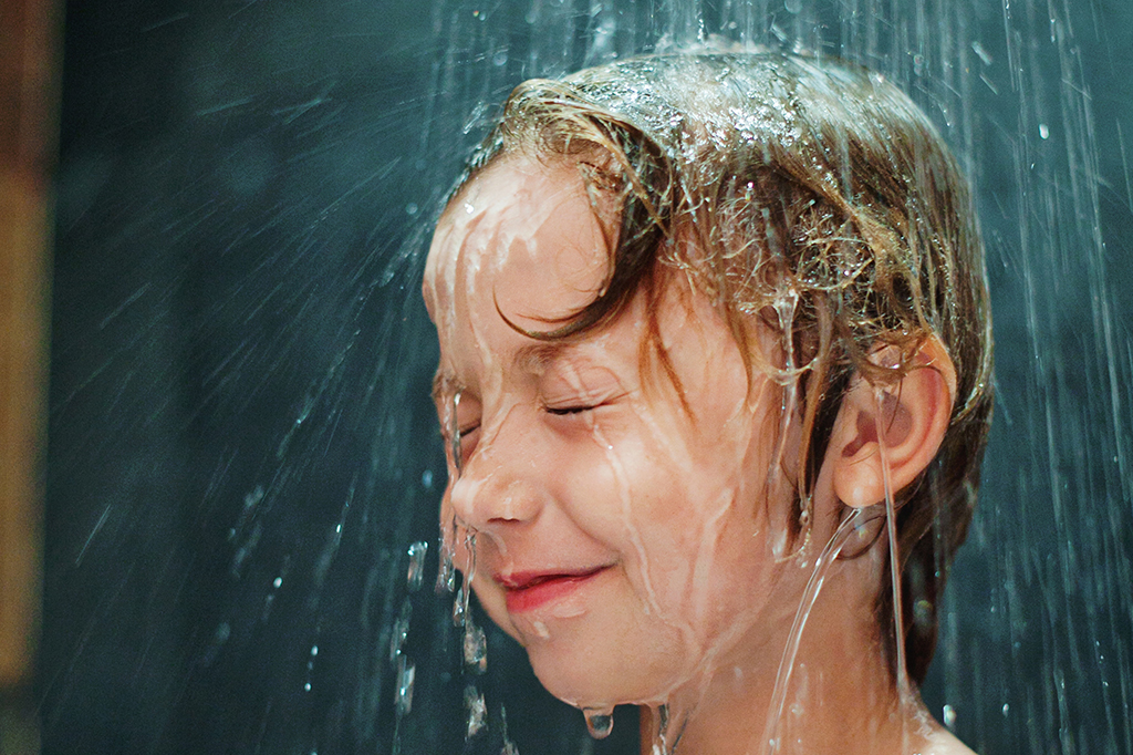 Criança tomando banho no chuveiro.