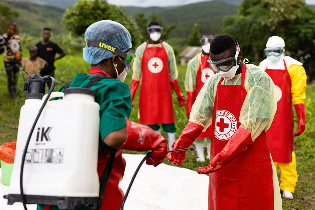Foto de trabalhadores da Cruz Vermelha de Uganda colocando EPI.