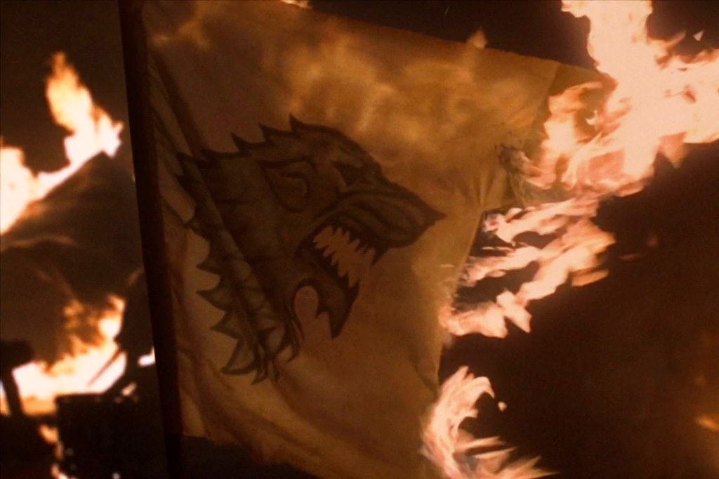 Fotografia de uma cena da série de televisão Game of Thrones em que a bandeira Stark é queimada.