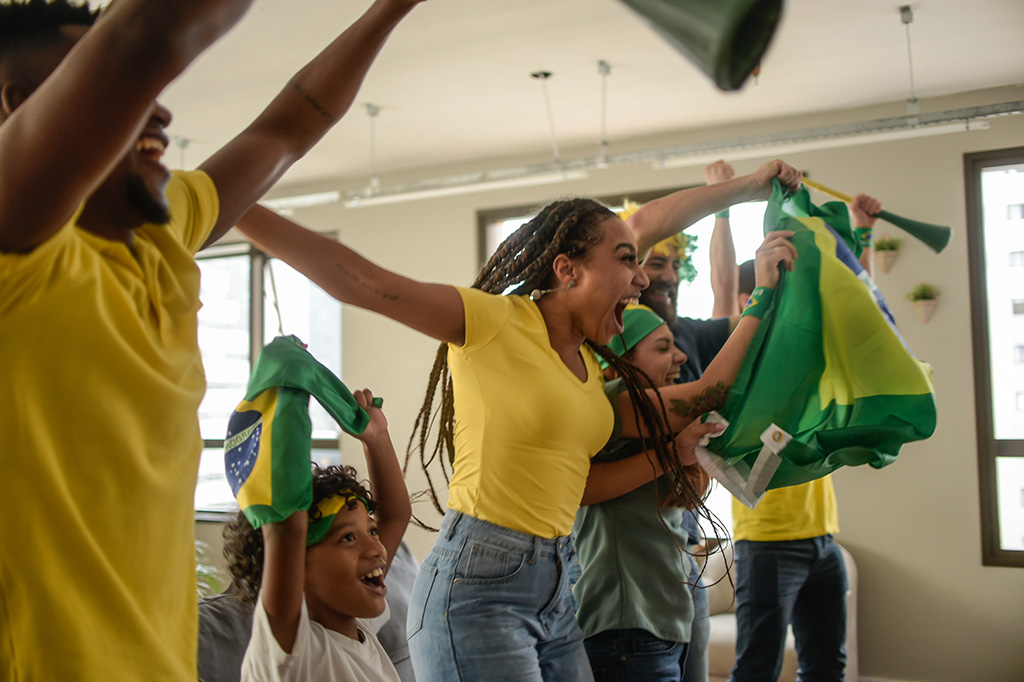 Fotografia de algumas pessoas comemorando com bandeiras do Brasil.