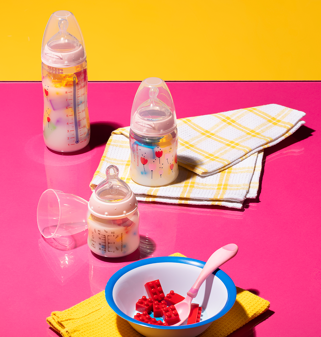 Foto de mamadeiras cheias de leite e plástico e uma tigela com pedaços de lego.
