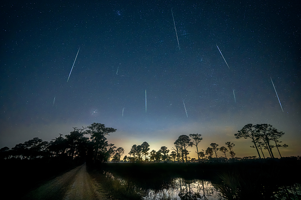 Fotografia de uma paisagem onde está acontecendo uma chuva de meteoros geminideas.