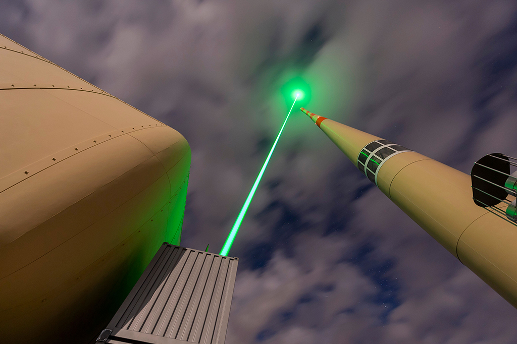 Foto vista de baixo de um feixe de laser verde apontado para o céu.