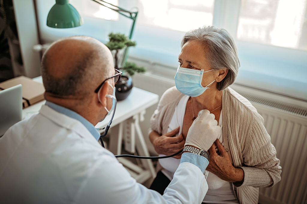 Médico usando estetoscópio para avaliar o coração de uma paciente idosa, em consultório.