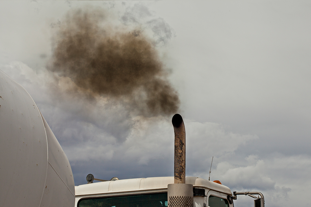 Um escapamento de caminhão soltando fumaça no ar.