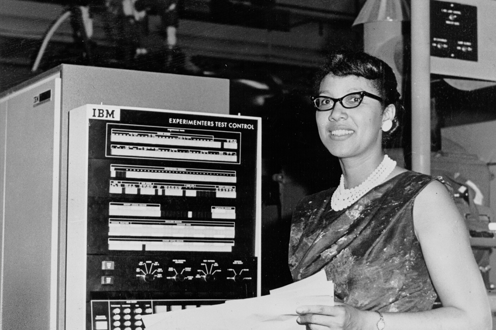 Fotografia de Melba Roy Mouton ao lado de um equipamento IBM.