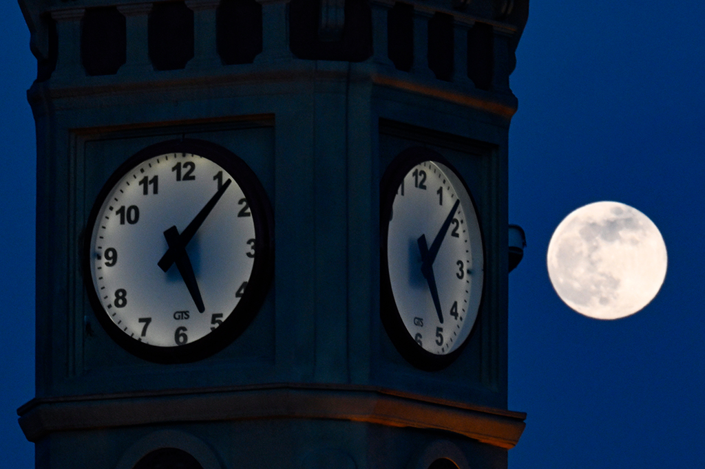 Foto da lua no céu, em perspectiva próxima ao relógio do Big Ben.