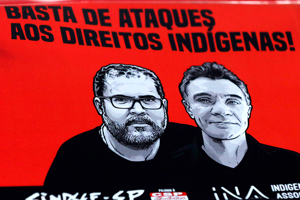 Poster pedindo o fim dos ataques ao direito indígenas com a foto do Bruno Pereira e Dom Phillips.