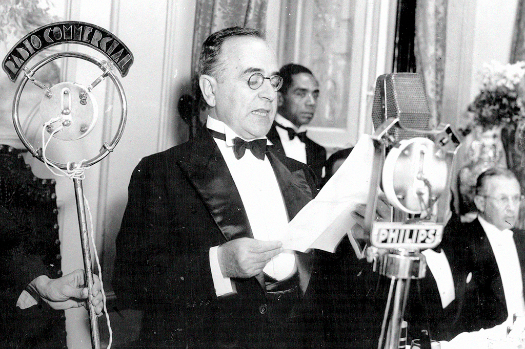 Getulio Dornelles Vargas lendo um papel a frente de um microfone.
