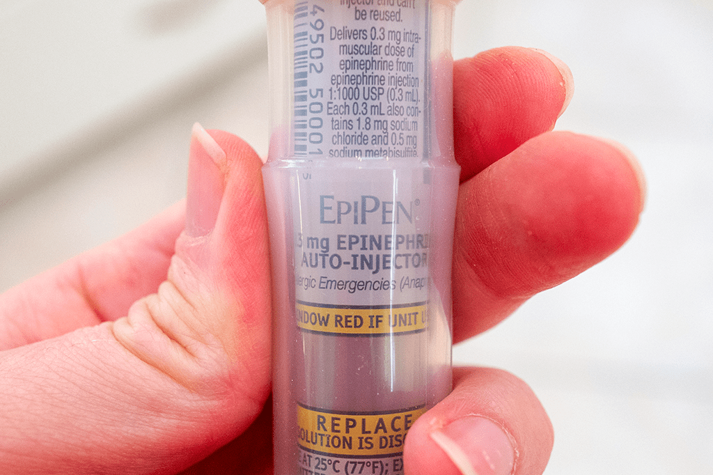 Foto de uma mão segurando uma EpiPen.