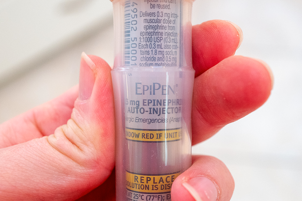 Foto de uma mão segurando uma EpiPen.