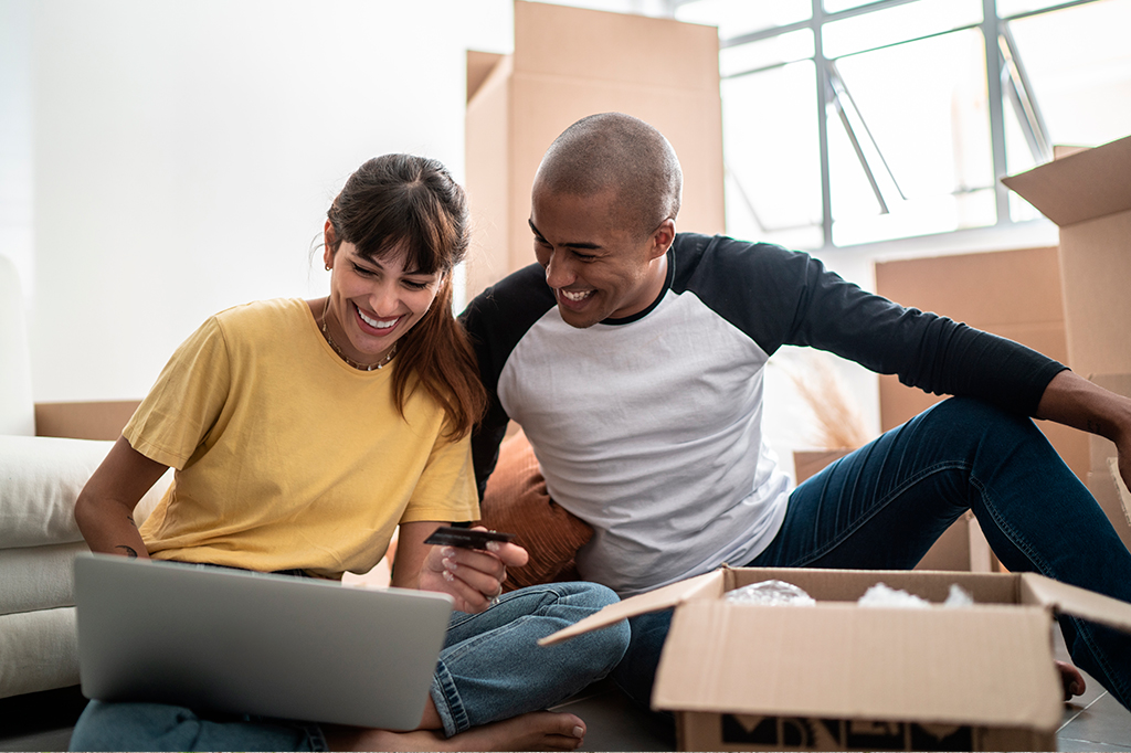 Foto de casal multirracial fazendo uma compra online para casa nova em casa.