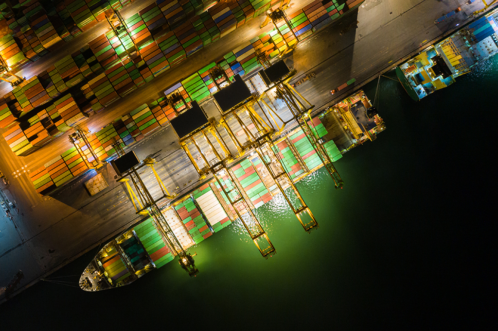 Vista aérea de navios de carga em porto com vários carregamentos de containers.