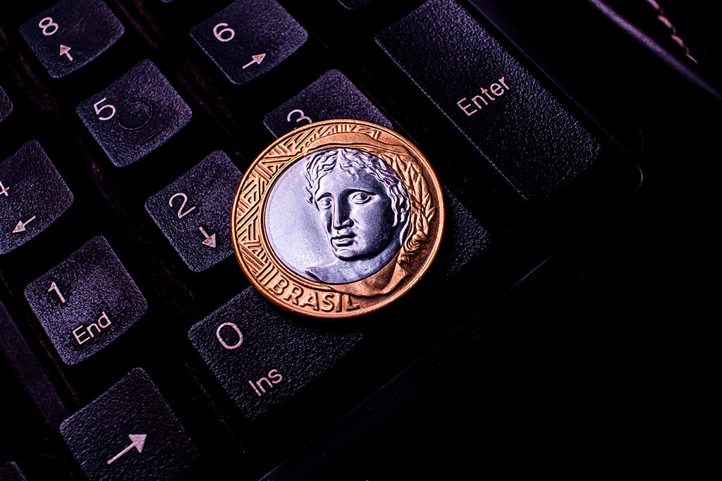 Foto aproximada de uma moeda de um real sob um teclado de computador.