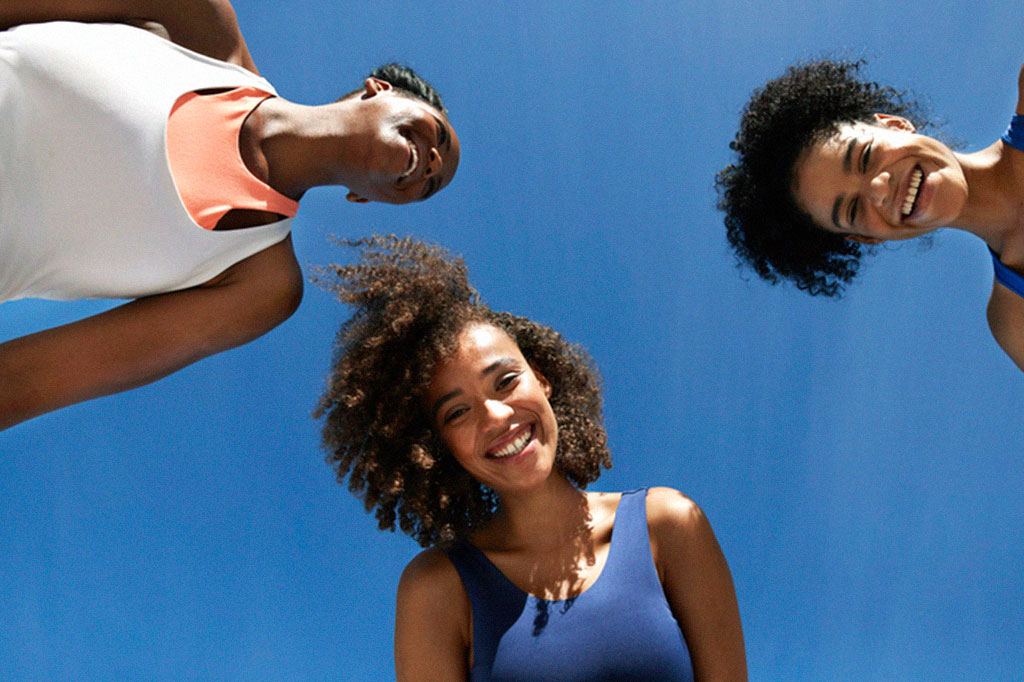 Foto de jovens esportistas negras felizes contra o céu azul em dia ensolarado.