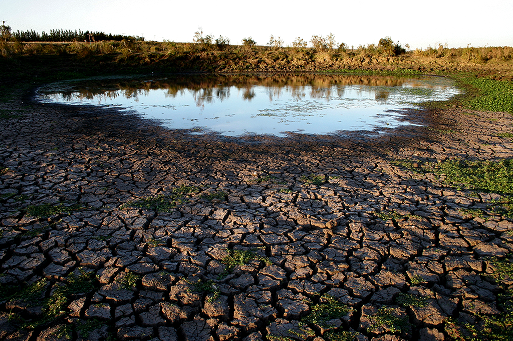 Imagem mostrando um lago secando, deixando o solo rachado.