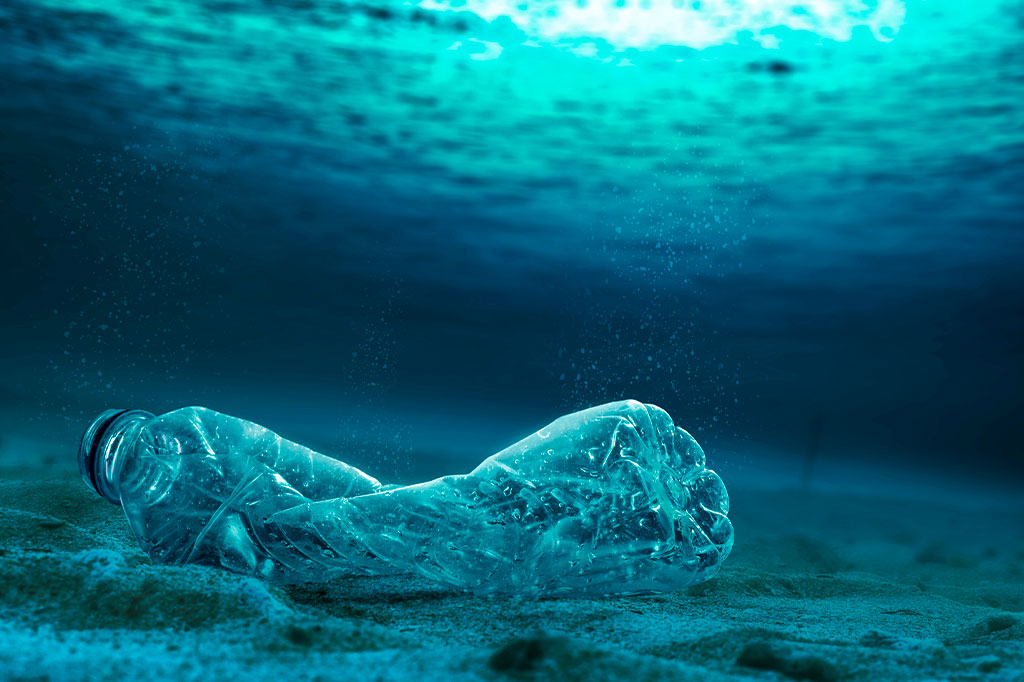 Foto de uma garrafa plástica no oceano.