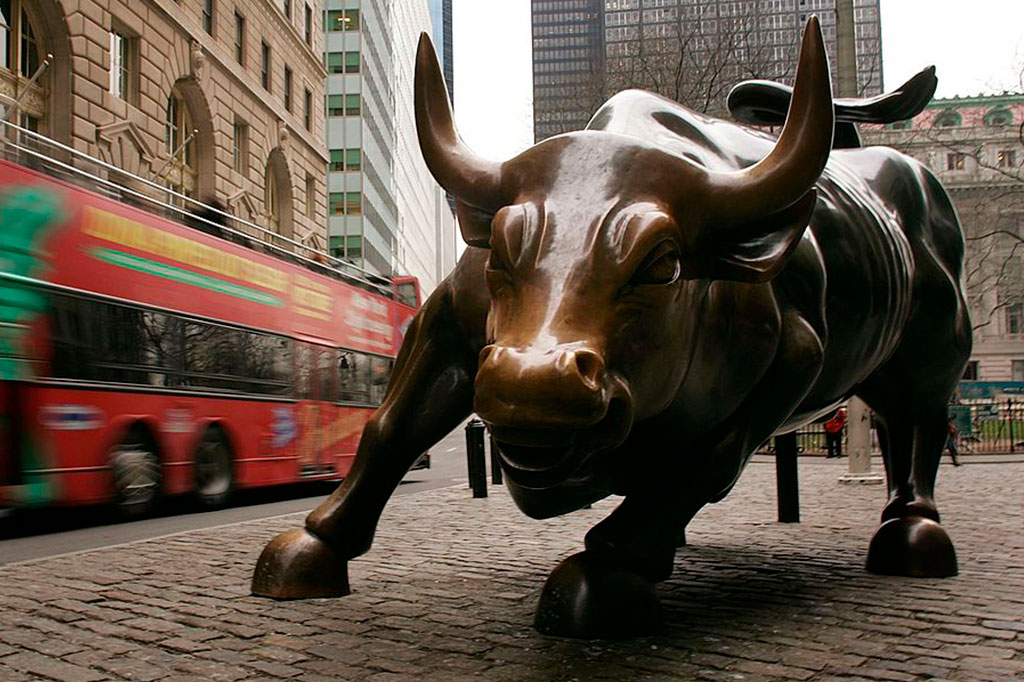 Um ônibus de excursão passa o touro de Wall Street no distrito financeiro.