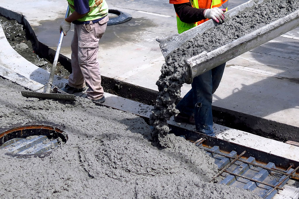 Foto aproximada de concreto sendo derramado para construção de calçada.