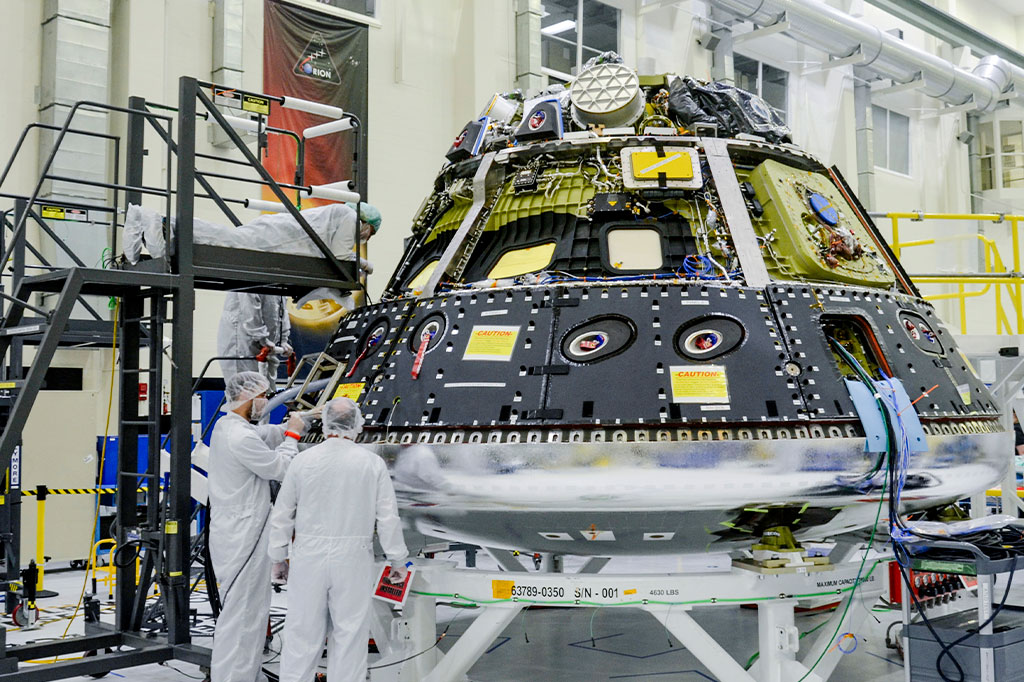 Os técnicos trabalham no módulo de tripulação Orion para a missão Artemis II da NASA dentro do Neil A. Armstrong Operations and Checkout Building no Kennedy Space Center da agência na Flórida.