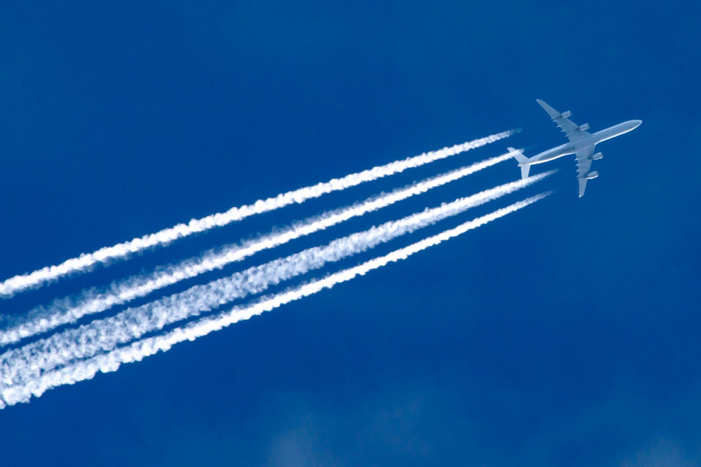 Foto de Jet transatlântico com quatro combinação de listras brancas contra o céu azul.