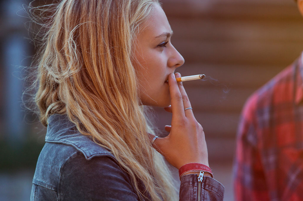 Mulher jovem loira fumando cigarro.