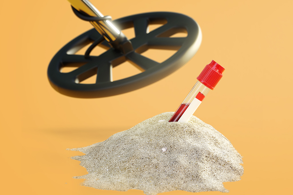 Imagem de um detector de metais encontrando uma ampola de sangue enterrada em um monte de areia.