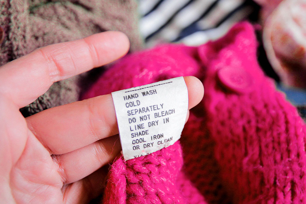 Foto aproximada da etiqueta da blusa com instruções de lavagem.