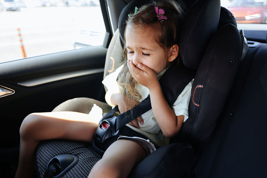 Menina sofrendo com enjoo de movimento no carro.