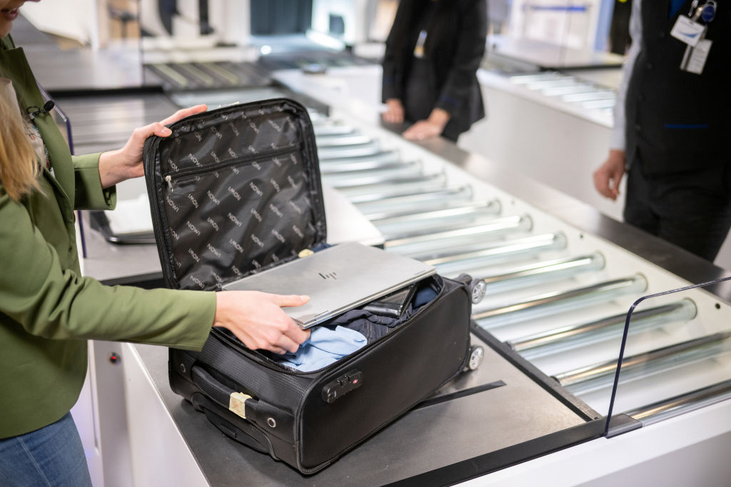 Uma mulher coloca um laptop em uma mala durante verificações de segurança da aviação no aeroporto de Frankfurt.