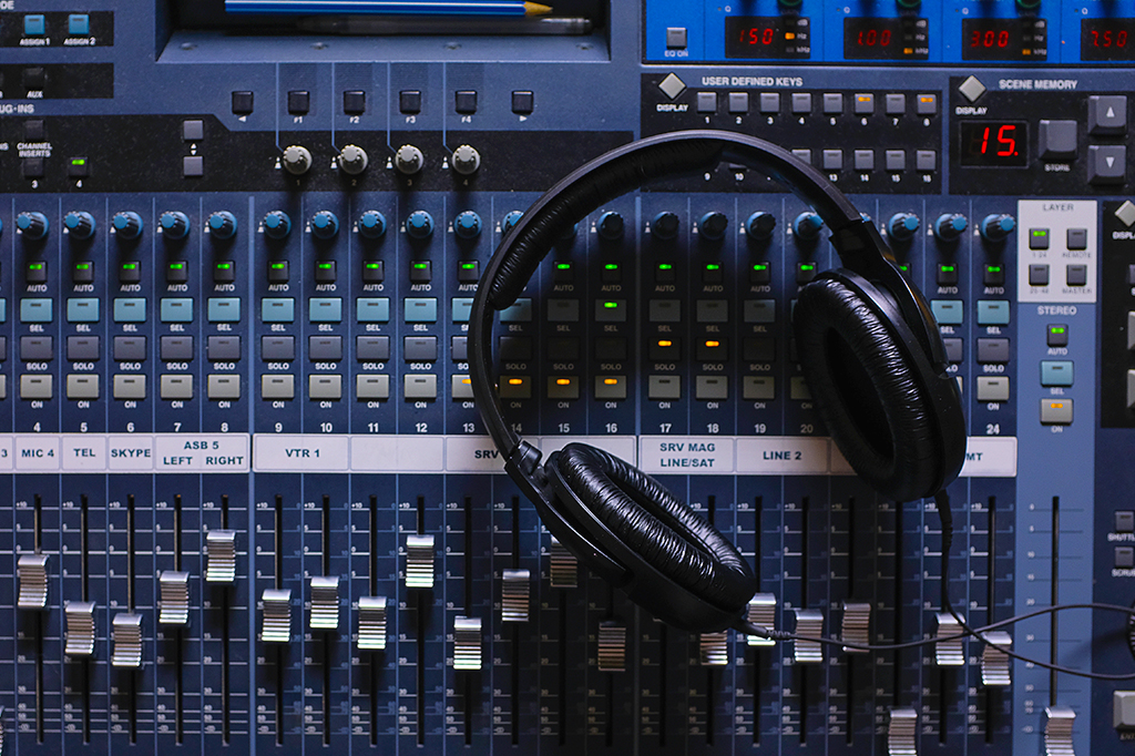 Foto de um fone de ouvido em cima de equipamentos de produção de música.