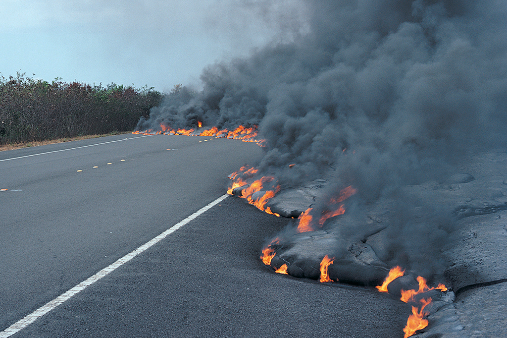 Lava flamejante destruindo uma estrada de asfalto.
