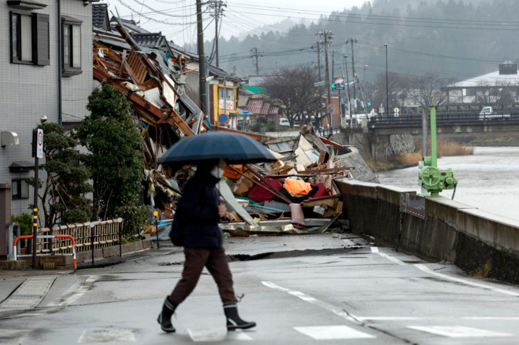 Uma mulher passa por casas desabadas em Wajima, província de Ishikawa, Japão