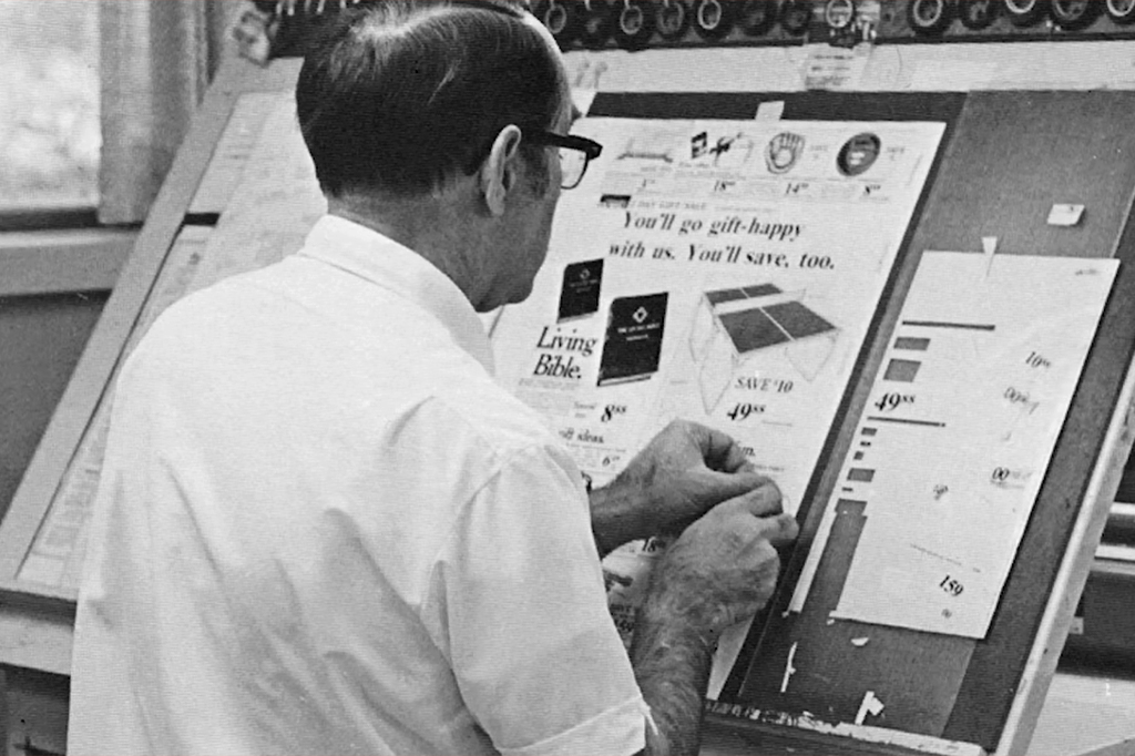 Imagem de um designers designer editorial criando layouts através do processo de recorte e colagem em uma página em branco.