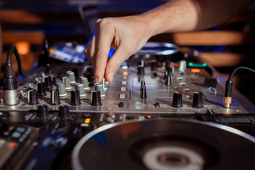 Fotografia de um DJ mexendo em aparelhos de mixagem.
