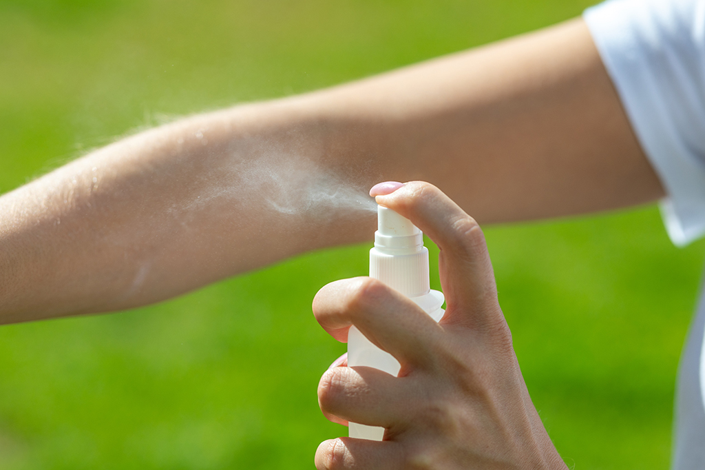 Fotografia de um repelente spray sendo aplicado diretamente em um braço.
