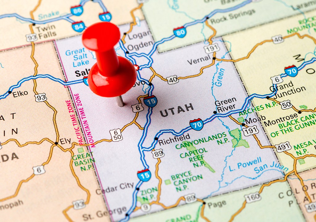 Alfinete destacando o estado de Utah, em um mapa impresso dos Estados Unidos.