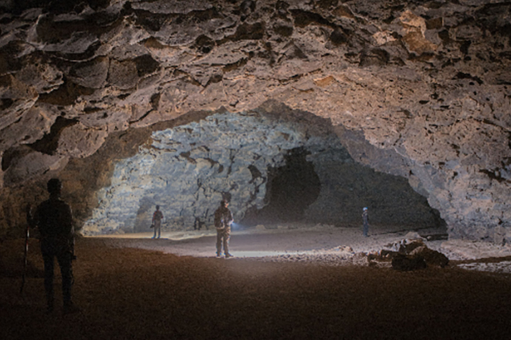 Interior de uma caverna com pessoas dentro.