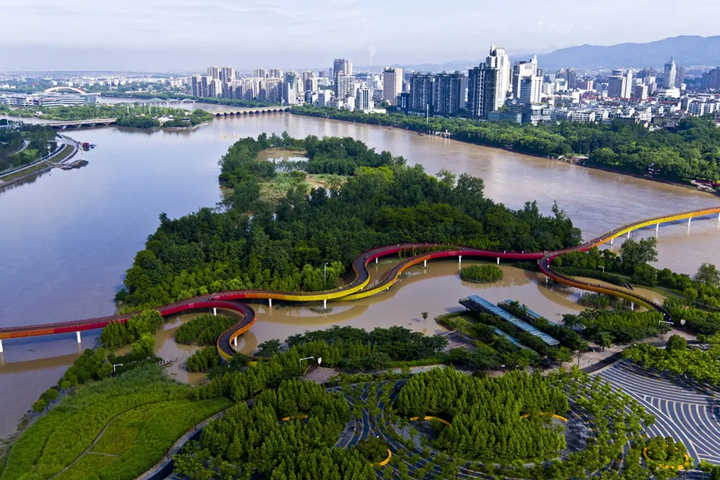 Vista aérea de uma cidade repleta de árvores em torno de um rio.