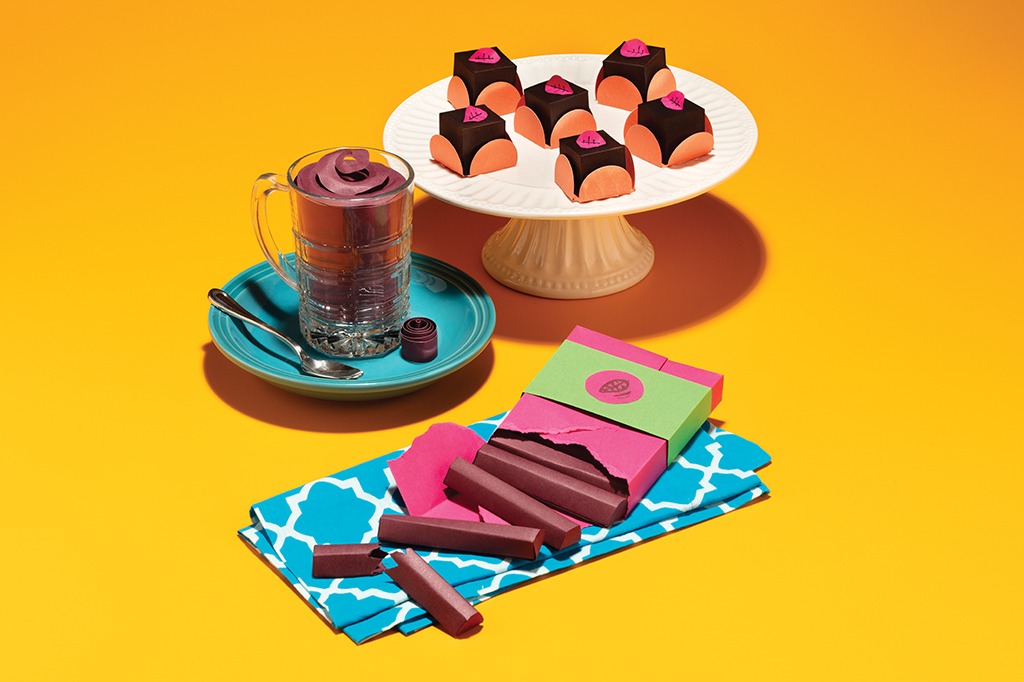Foto de bombons de chocolate, uma xícara com chocolate quente e uma barra de chocolate, todos feitos de papel.