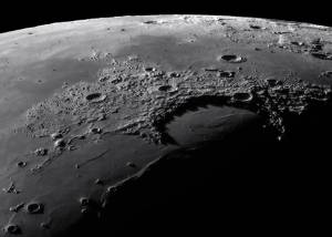 1609-astronomy-photographer-Gabor-Balazs Esta fotografia mostra Sinus Iridum, também conhecida como Baía dos Arco-Íris, uma cratera de impacto com 260 quilómetros de diâmetro, rodeada por várias crateras mais pequenas. O fotógrafo usou uma câmera monocromática com filtro para capturar a área. A cratera visível no canto superior direito, Pitágoras, é particularmente notável e é quase visível de lado devido à libração, a oscilação da Lua vista da Terra.