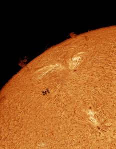 Esta imagem H-alfa do Sol apresenta a silhueta da Estação Espacial Internacional transitando pelo limbo solar oriental. Cruzando o campo de visão em apenas 0,2 segundos, os trânsitos do Sol na ISS são particularmente raros a partir de qualquer local da Terra. O sol estava ativo e um destaque pode ser visto logo ao lado do local de trânsito da estação