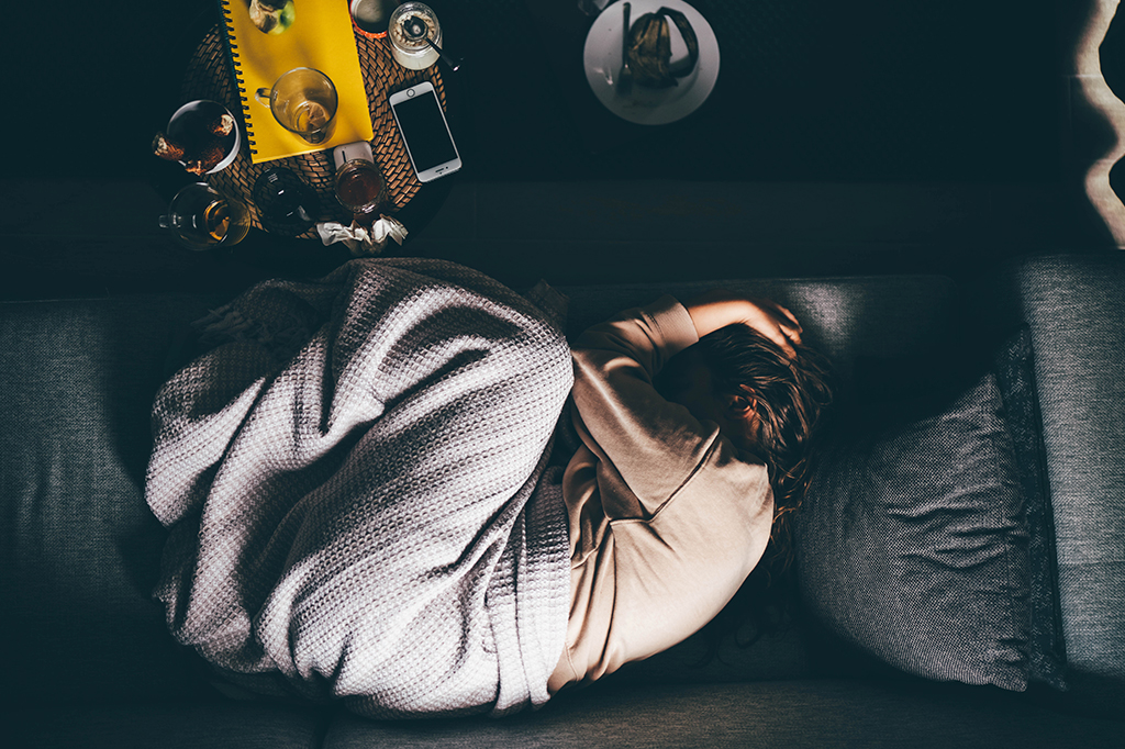 Foto de Jovem com depressão deitada no sofá em casa.