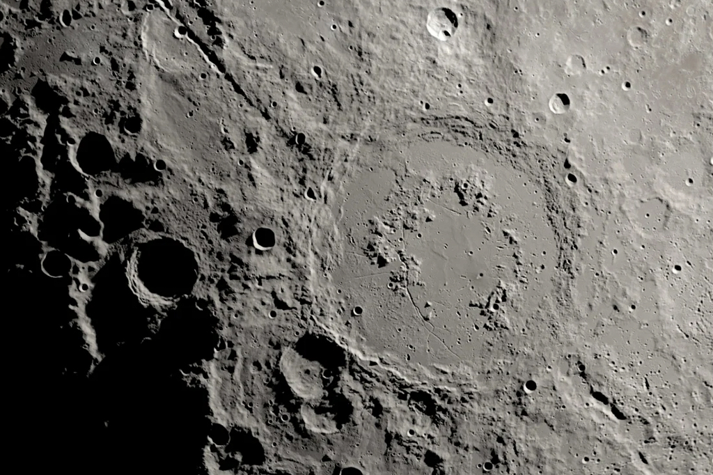 Fotografia dos detritos do impacto que criou a bacia de Schrödinger formaram cânions profundos que podem ser vistos fluindo para longe da cratera nesta imagem do Lunar Reconnaissance Orbiter.