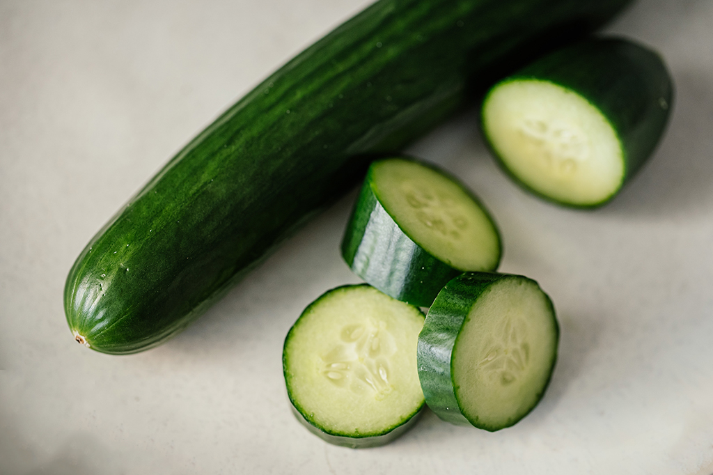 Fotografia de um pepino e fatias do pepino.