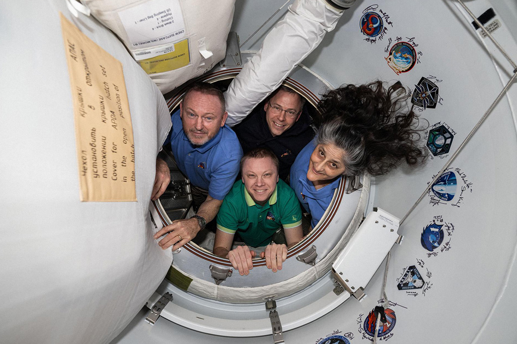 Foto dos membros da missão SpaceX Crew-9, da Nasa, posando juntos no portal que conecta a Estação Espacial Internacional (ISS) à nave SpaceX Dragon, que vai trazer os astronautas de volta para a Terra.