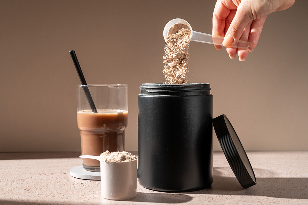 Fotografia de Shake de proteína e cearatina em pó de chocolate em uma colher, suplemento alimentar.