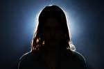 Fotografia de uma mulher no escuro com uma luz forte branca atrás dela.