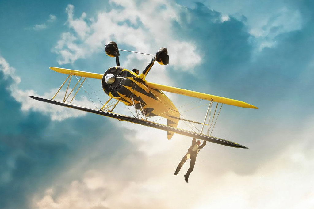 Imagem de um homem pendurado nas asas de um avião biplano amarelo. Cena do filme Missão: Impossível 8.